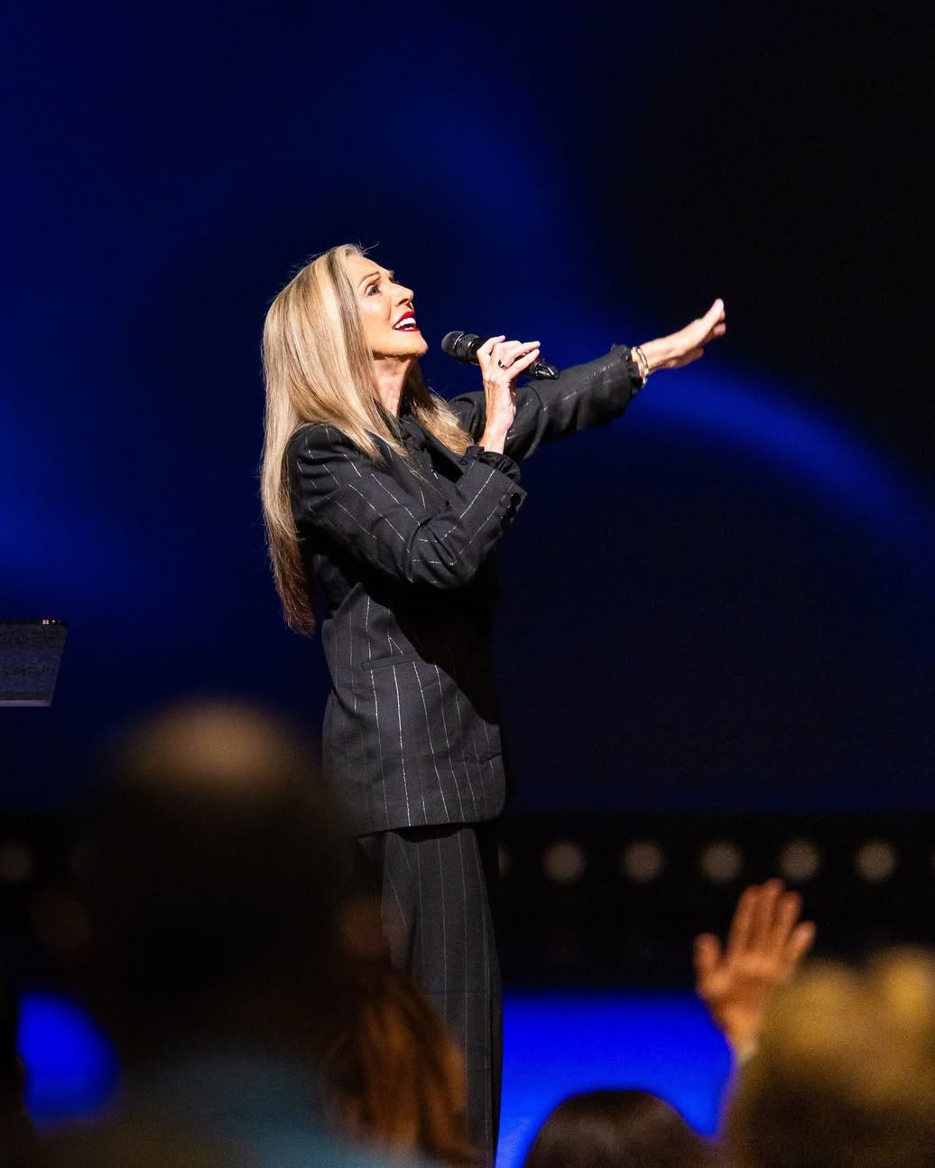 Cheryl Salem worshiping on stage with hand raised